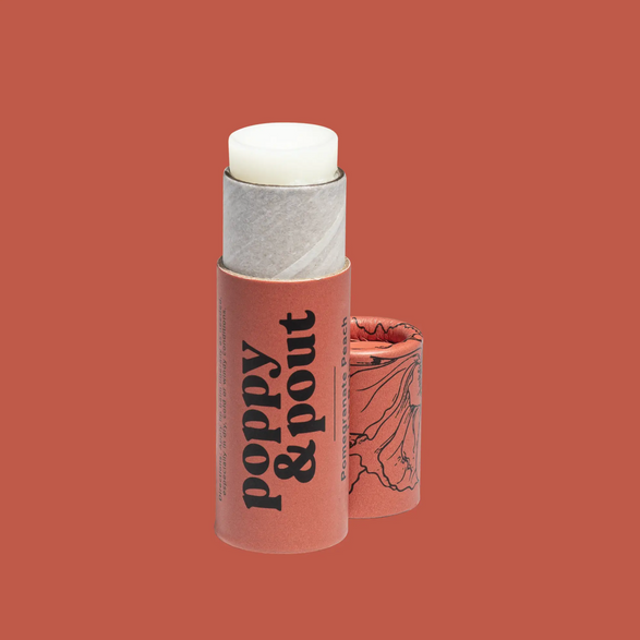An image of an open grapefruit pink lip balm paper tube with text "poppy and pout" on a grapefruit pink background