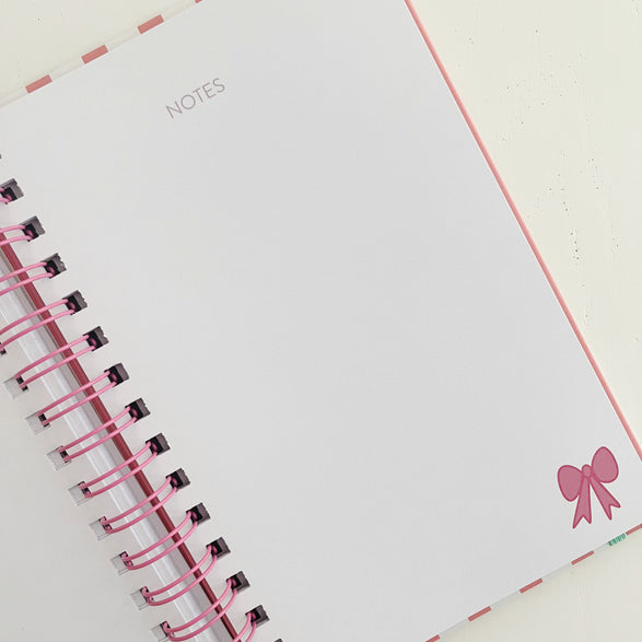 Notebook with pink ribbon and decorative bow on a white background
