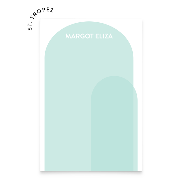 A notepad with text that reads "Margot Eliza" and an illustration of two light blue arches overlapping