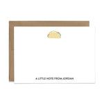 Image of a white flat note card and a kraft brown envelope. The card has a cute taco illustration at the top and an example of a name at the bottom.