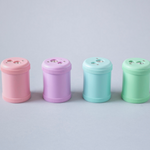 Image of four pastel pink, purple, blue and mint green pencil sharpeners with two different size openings on a grey background