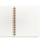 An image of an open notebook with dot grid paper and gold spiral binding