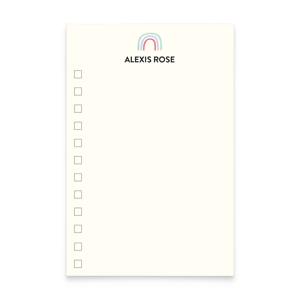 A photo of a notepad with a rainbow illustration and text that reads "Alexis Rose" at the top with check boxes down the left side