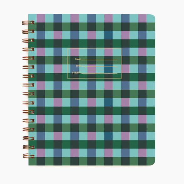 An image of a green, blue and purple plaid notebook with gold spiral binding on a white background. The cover of the notebook has a small section to label the name, date and subject.